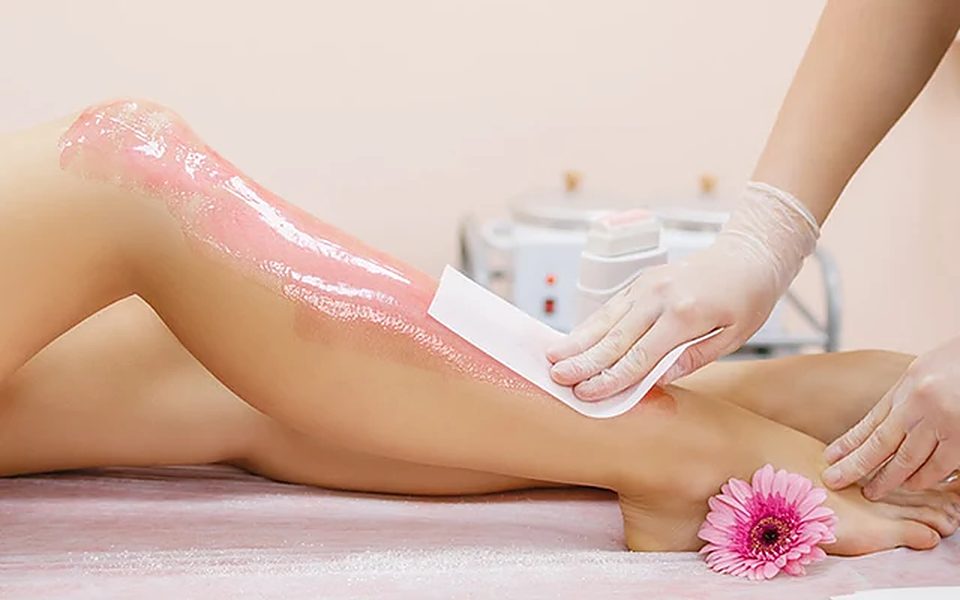 Leg waxing treatment with a pink flower beside the foot
